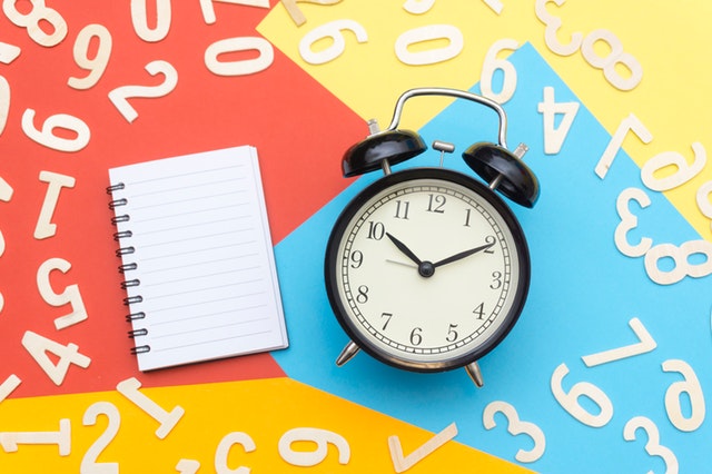 alarm-clock-lying-on-multicolored-surface-1314544